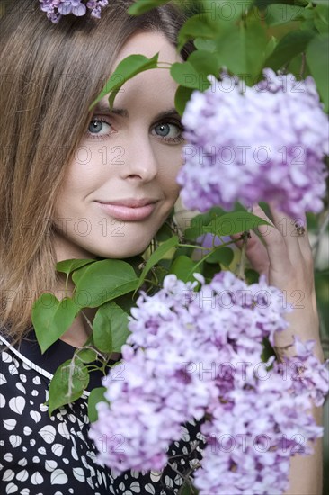 Closeup portrait of happy girl near lilac tree in sity park