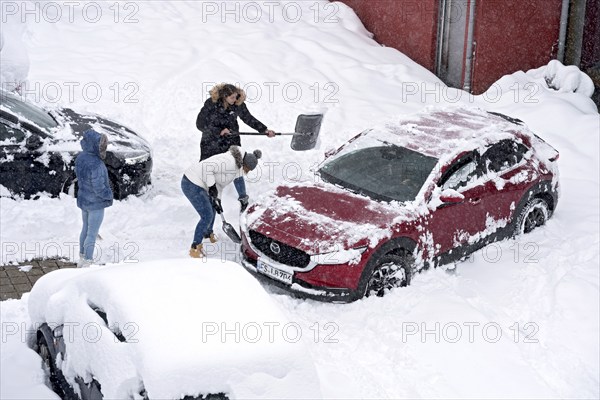 Women shovelling snow on car park, car, car, snowed in, fresh snow, heavy snowfall, snow masses, snow chaos, snow shovel, onset of winter, Marzling, Freising, Upper Bavaria, Bavaria, Germany, Europe