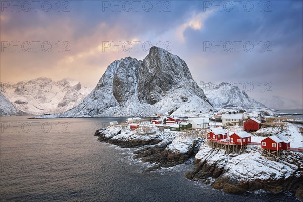 Famous tourist attraction Hamnoy fishing village on Lofoten Islands, Norway with red rorbu houses. With falling snow in winter on sunrise