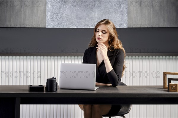 Young woman waiting for connection of online call in the office sitting behind the desk