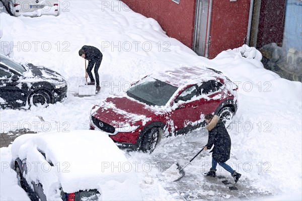 Man and woman shovelling snow on car park, car, car, snowed in, fresh snow, heavy snowfall, snow masses, snow chaos, snow shovel, onset of winter, Marzling, Freising, Upper Bavaria, Bavaria, Germany, Europe