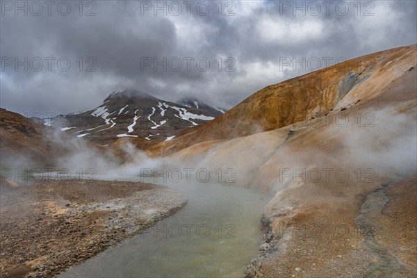 Steaming stream between colourful rhyolite mountains with snowfields, Hveradalir geothermal area, Kerlingarfjöll, Icelandic highlands, Iceland, Europe