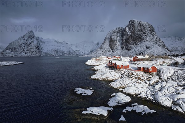 Iconic Hamnoy fishing village on Lofoten Islands, Norway with red rorbu houses. With falling snow in winter