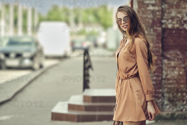 Young happy woman walking on the street in short dress listening to the music and dancing