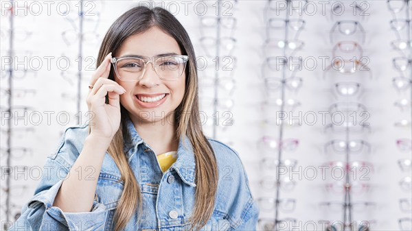 Attractive girl modeling glasses in an eyewear store. Portrait of Happy young woman wearing eyeglasses in an optical store