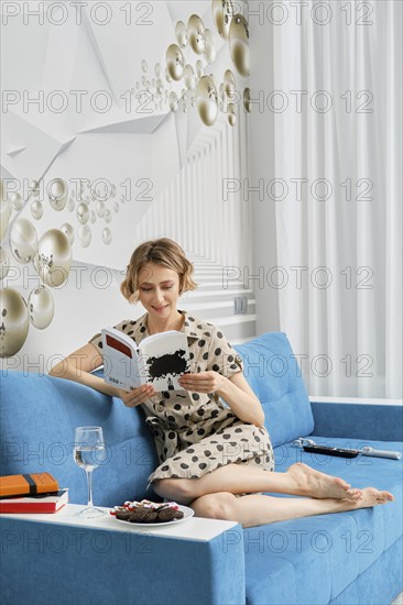 Barefoot woman sitting on sofa and reading the book