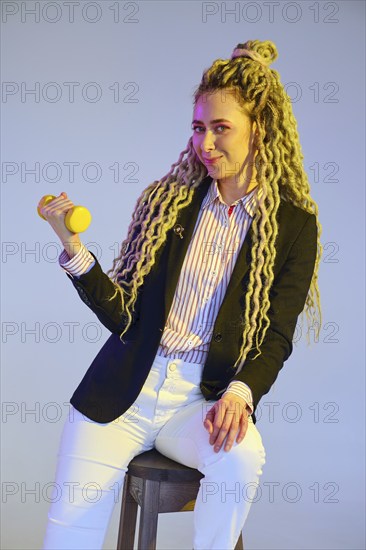 Woman power concept, girl in jeans and jacket with dreadlocks pumps dumbbell