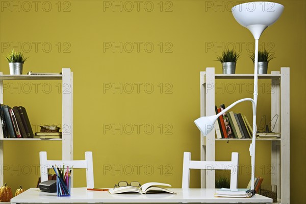 Empty desk with open book and glasses. Dormitory room with bookshelves