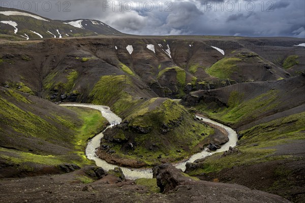 River bend, foot Asgardsa, volcanic landscape with black rocks and green moss, dramatic cloudy sky, Kerlingarfjöll, Icelandic highlands, Iceland, Europe