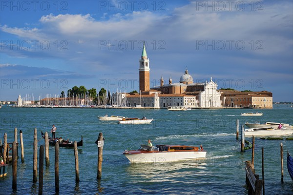 VENICE, ITALY, JUNE 27, 2018: Taxi boats in the lagoon of Venice by Saint Mark (San Marco) square with San Giorgio di Maggiore church in background in Venice, Italy seen from Ponte della Paglia