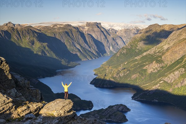 Hiker looking from Seiskallåfjellet into the Nordfjorden, Svartisen Glacier in the background, Saltfjellet Svartisen National Park, Helgeland Coast, Rødøy, Nordland, Norway, Europe