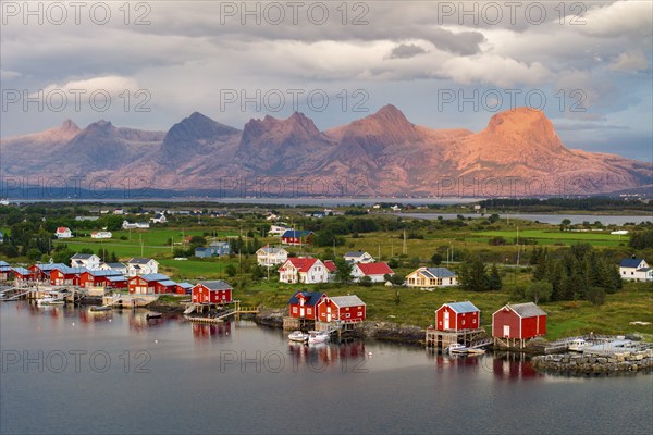 Boathouses of the village Herøy, behind the mountain range Seven Sisters, light mood, island Herøy, Helgeland coast, Nordland, Norway, Europe