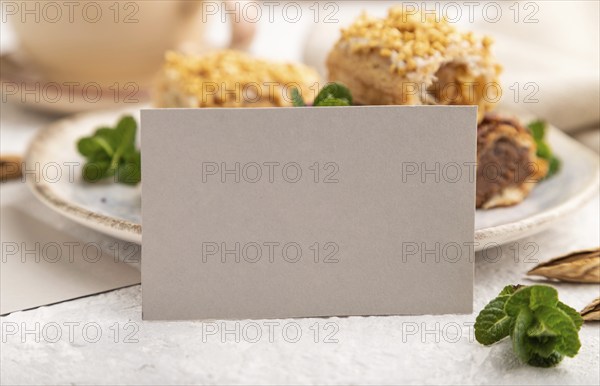 Gray paper business card and set of eclair on gray concrete background. side view, close up, selective focus, still life. Breakfast, morning, concept