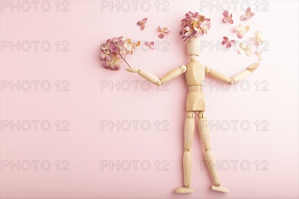 Wooden mannequin holding hydrangea flowers on pink pastel background. copy space, isolated, spring, gardening concept