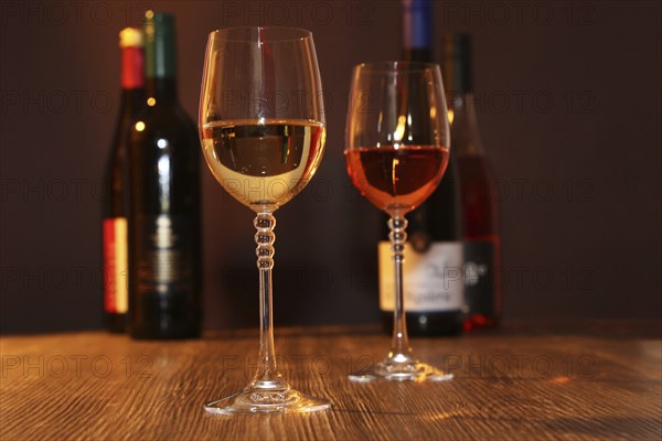 Close-up of two glasses of wine with wine bottles in the background