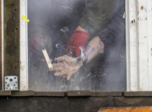 2nd day of the eviction of the hamlet Lützerath, by the police, of tree houses and huts, activist has glued herself to the glass pane of a window, from the inside, police removes the glue, at the opencast lignite mine Garzweiler 2, Erkelenz, North Rhine-Westphalia, Germany, Europe