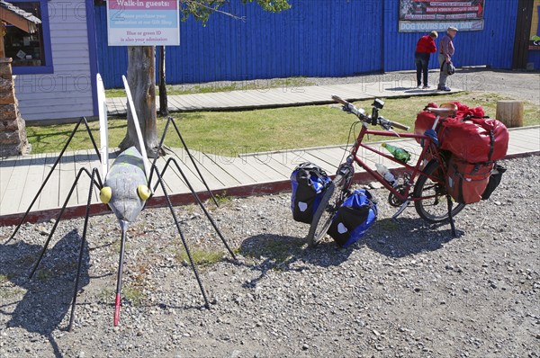 Bicycle with luggage next to an oversized mosquito, Carcross, Yukon Territory, Canada, North America