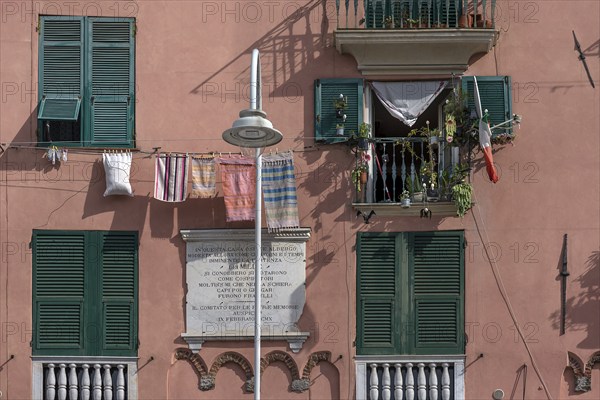 Residential building façade with green shutters and hanging laundry in the historic city centre, Genoa, Italy, Europe