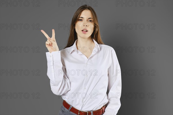 Young woman shows two fingers or victory sign. Counting with fingers concept