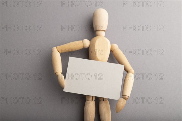 Wooden mannequin holding blank poster on gray pastel background. copy space, isolated, presentation concept