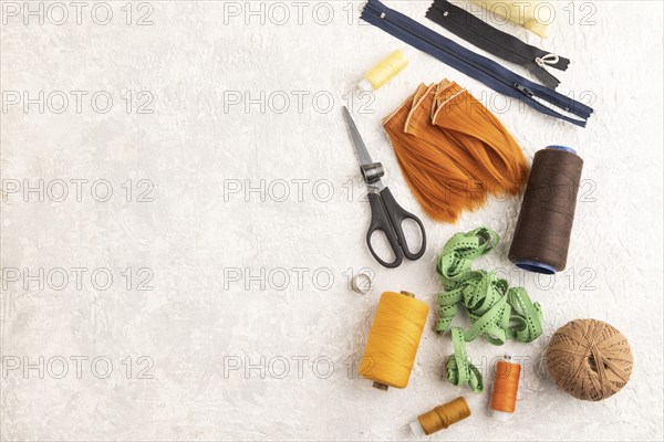 Sewing accessories: scissors, thread, thimbles, braid on gray concrete background. Top view, flat lay, copy space