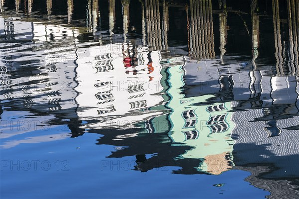 Pier at harbor in Henningsvær, reflections of wooden houses in the calm water, Austvagøy, Lofoten, Norway, Europe