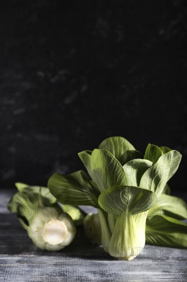 Fresh green bok choy or pac choi chinese cabbage on a gray wooden background. Hard light, contrast, dark, moody. Side view, copy space, selective focus