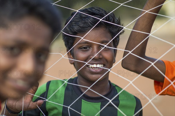 Laughing boys looking through goal net, football, Parade Ground, Fort Cochin, Kochi, Kerala, South India, India, Asia