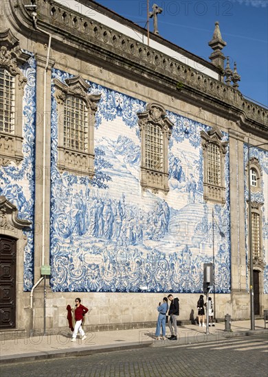 People pass by the facade of Igreja do Carmo church, adorned with intricate blue and white tiles, Porto, Portugal, Europe