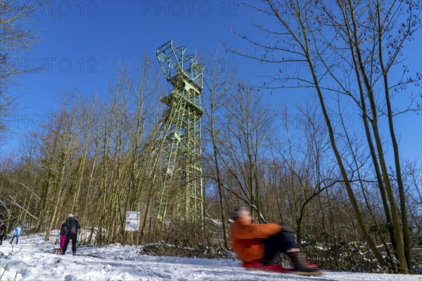 Winter in the Ruhr area, toboggan run on a forest path at Lake Baldeney, headframe of the former Carl Funke colliery, Essen, North Rhine-Westphalia, Germany, Europe