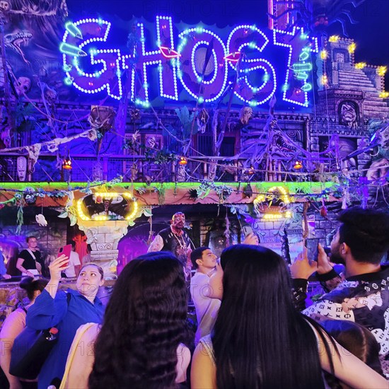 People in front of the illuminated ghost train Ghost in the evening, Cranger Kirmes, Herne, Ruhr area, North Rhine-Westphalia, Germany, Europe