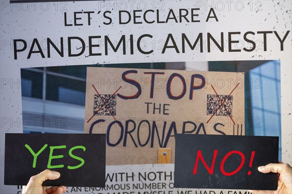 Symbolic image of Pandemic Amnesty: Section of a symbolic newspaper, signs reading YES and NO are held in front of it. In the USA and many other countries, a debate has begun on coming to terms with the coronavirus measures