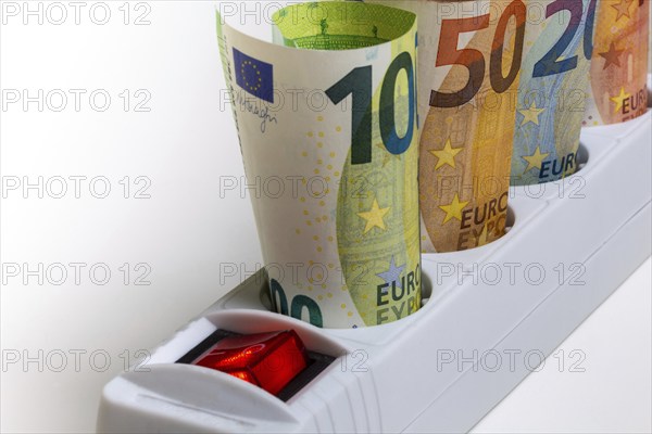 Symbolic image of electricity costs: Multiple socket outlet with banknotes