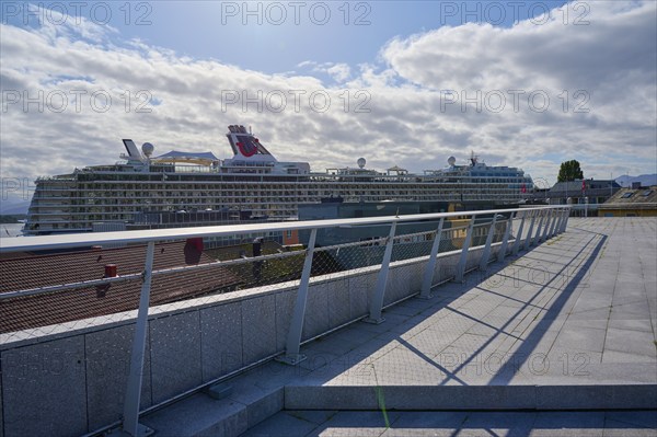 View from the event terrace More og Romsdal Art Centre to cruise ship, Mein Schiff 6, in the harbour on a sunny day with cloudy sky and architectural railing in the foreground, Molde, Romsdal, Norway, Europe