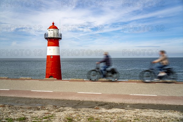 North Sea dyke near Westkapelle, Westkapelle Laag lighthouse, cyclists on the Zeeuwse Wind Route cycle path, province of Zeeland, Walcheren peninsula, Netherlands