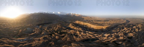 Panorama, White glaciated and snow-covered mountain peak Pik Lenin at sunrise, hilly landscape with golden meadows and lakes, aerial view, Trans Alay Mountains, Pamir Mountains, Osh Province, Kyrgyzstan, Asia