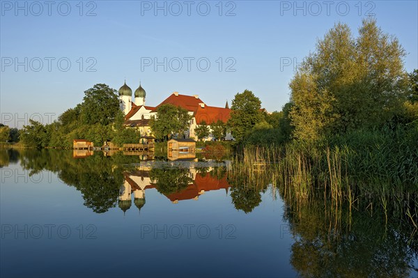 Romanesque Benedictine Abbey Seeon Monastery, monastery church St. Lambert with reflection in the monastery lake, calm smooth water in the evening light at sunset, Seeon-Seebruck, Chiemgau, Upper Bavaria, Bavaria, Germany, Europe