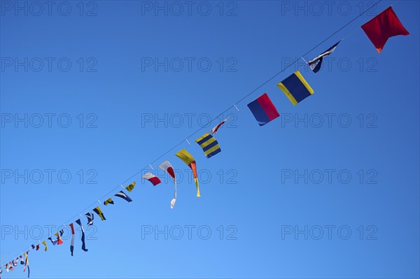 Several colourful flags hanging on a line in front of a clear blue sky, Hamburg, Germany, Europe