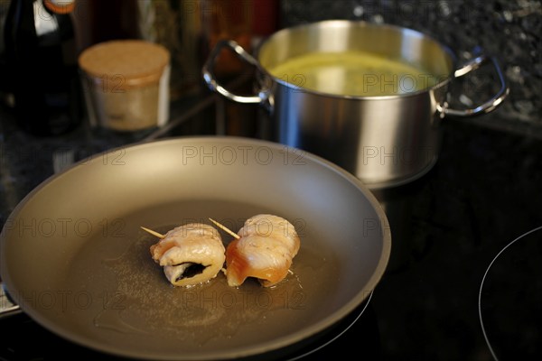 Southern German cuisine, preparation of sorrel soup with char, frying raw char fillets in a pan, oil, freshwater fish, savoury, salty, cooking pot with vegetable stock in the back, traditional cuisine, food photography, studio, Germany, Europe