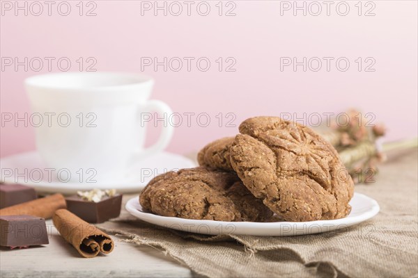 Homemade oatmeal cookies with a cup of cocoa on a linen textile and pink pastel background. side view, close up, selective focus