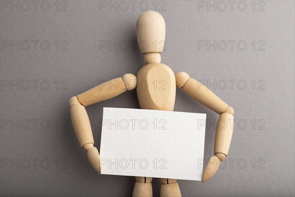 Wooden mannequin holding blank poster on gray pastel background. copy space, isolated, presentation concept