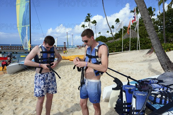 Two men prepare for sailing on sunny tropical beach, catamaran trip, Dominicus beach, Bayahibe, Dominican Republic, Hispaniola, Caribbean, America, Central America