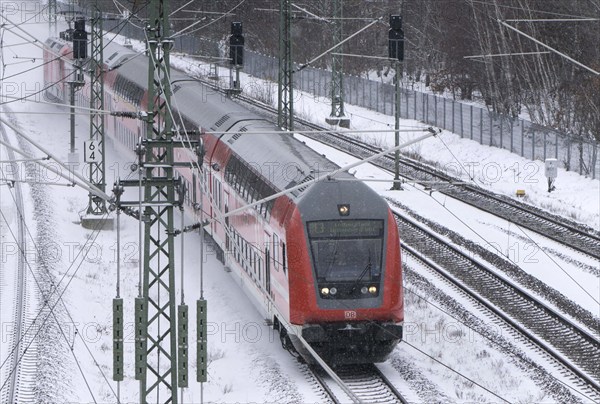 A Deutsche Bahn regional train runs over snow-covered railway tracks and stirs up snow, Berlin, 09/02/2021