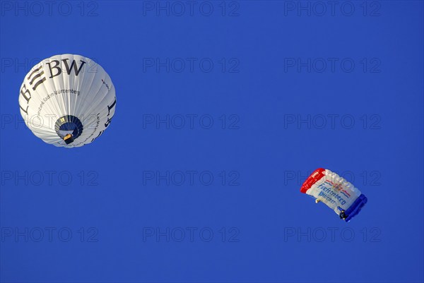 Landesbank BW hot air balloon and parachutist with open parachute in the air, as part of the aviation festival on the Rossfeld in Metzingen-Glems, Metzingen, Baden-Württemberg, Germany, 11 September 2010, for editorial use only, Europe