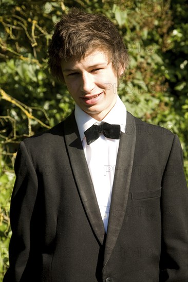 Model released portrait of young man wearing bow tie and suit jacket dressed for his school prom, UK