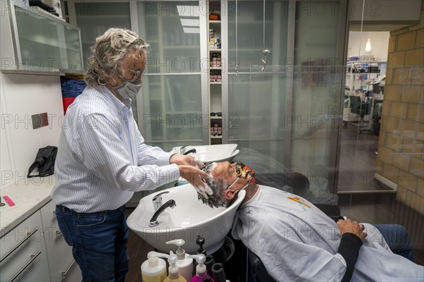 Hairdressing salon in Essen-Rüttenscheid, first customer after 6 weeks, shop closed due to Corona, hairdresser and customer with mouth-nose protection, breathing mask, Plexiglas protective walls, spit protection, when washing hair, distance regulation, Essen, North Rhine-Westphalia, Germany, Europe