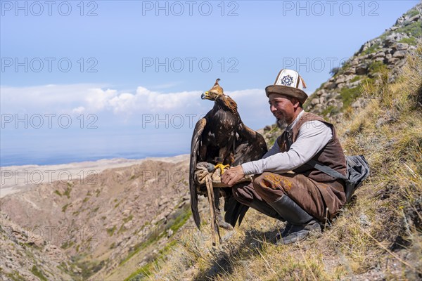 Traditional Kyrgyz eagle hunter with eagle in the mountains, near Kysyl-Suu, Kyrgyzstan, Asia