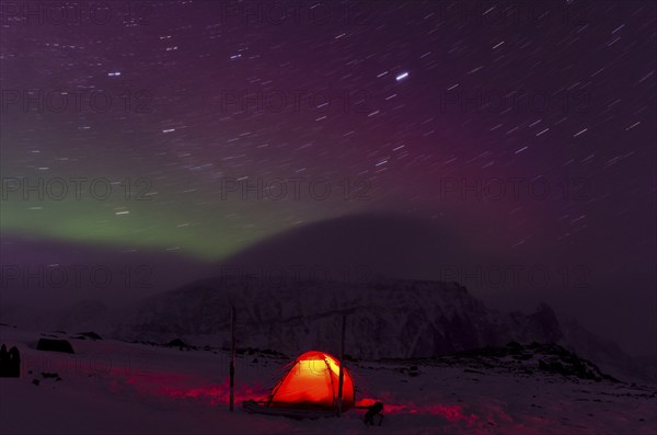 Northern Lights (Aurora borealis) and star trails above an illuminated tent in the valley Stuor Reaiddávággi, Kebnekaisefjaell, Norrbotten, Lapland, Sweden, Bivouac, Scandinavia, Europe