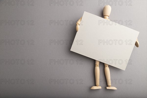 Wooden mannequin holding gray blank poster on gray pastel background. copy space, isolated, presentation concept