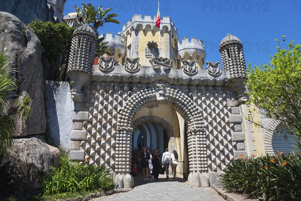 Entrance gate of a castle with decorative stone patterns and plants, visitors are visible, Palácio Nacional da Pena, National Palace Pena, Sintra, Lisbon, World Heritage Site, UNESCO, Portugal, Europe